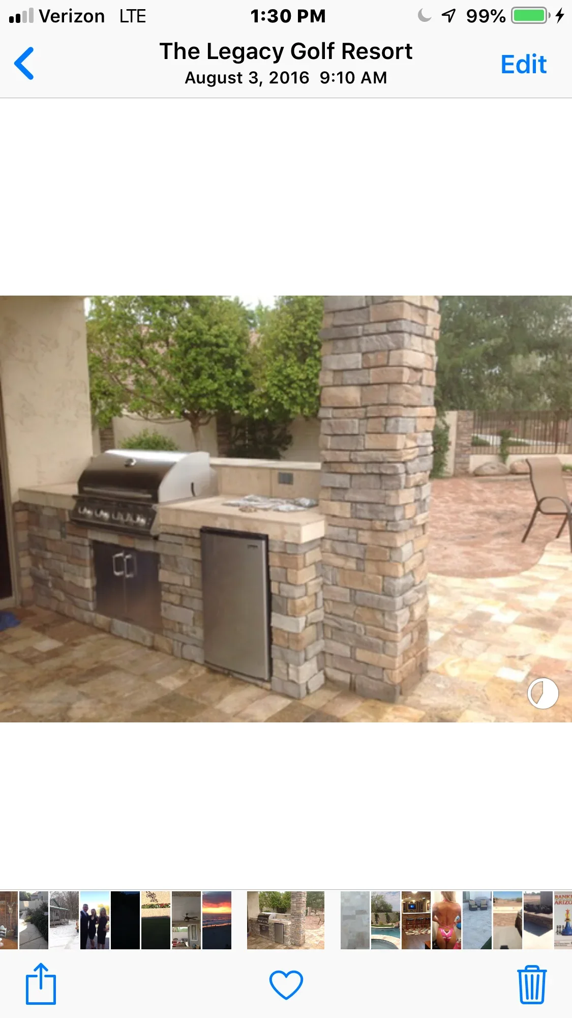 Stone outdoor kitchen island with grill and refrigerator on brick patio