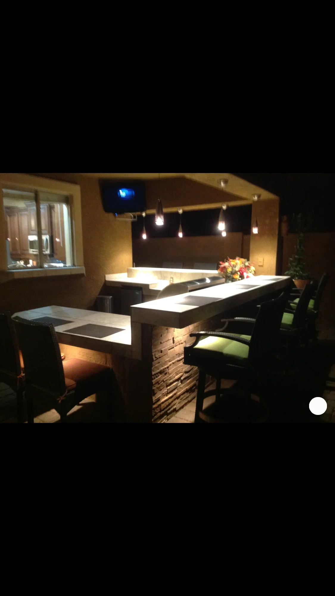 Illuminated outdoor bar patio with LED counters, pergola, and seating at night