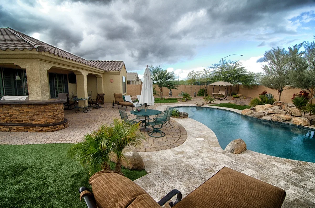 Desert backyard with resort pool, travertine patio, and desert landscaping in Mesa